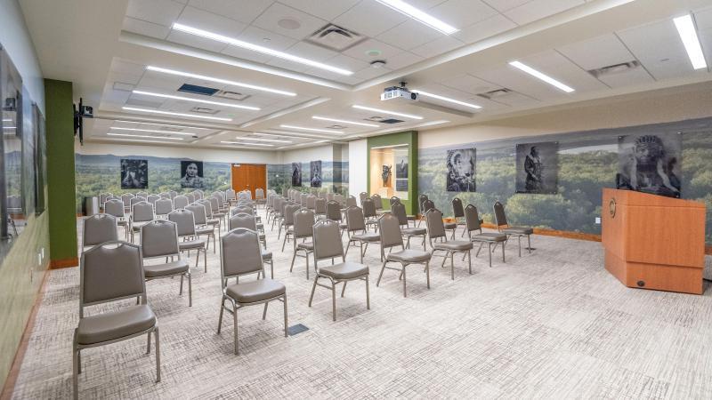 The Apple Creek Conference Room setup for a presentation features wet-plate photos of Native Americans overlaying a wall wrap of the Missouri River Valley.