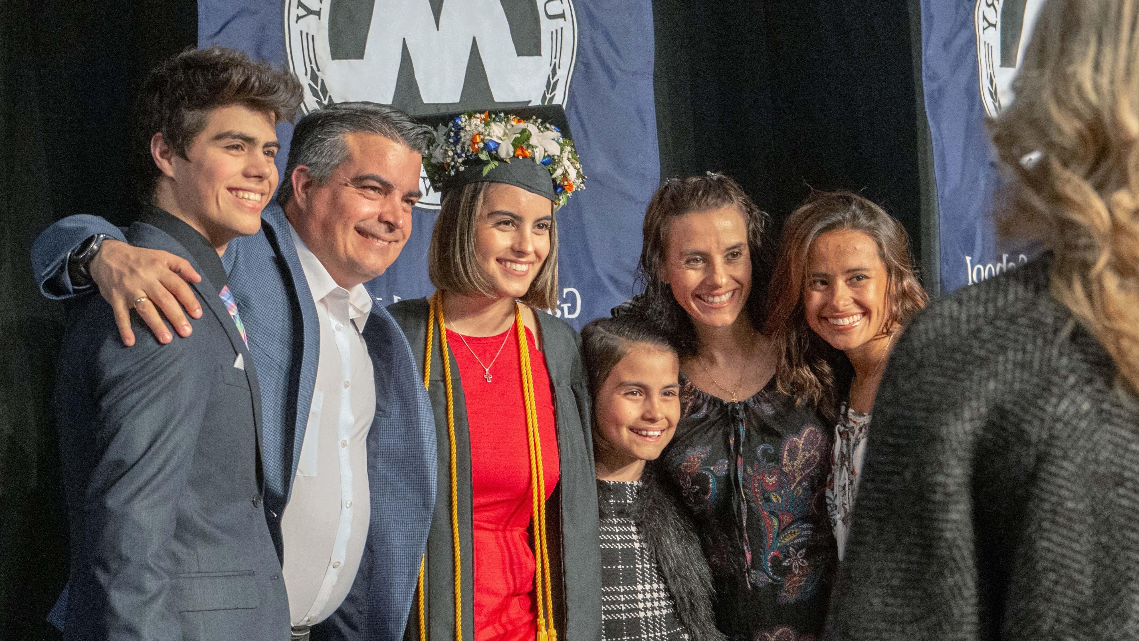 Graduate gathered with family for a photo at commencement
